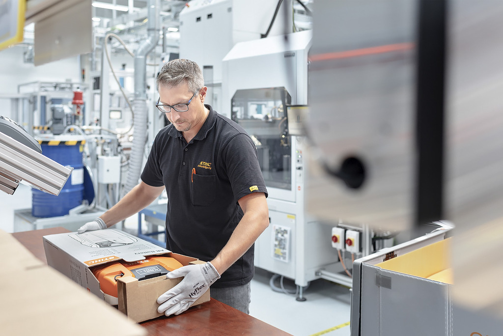 An employee in battery production packs a STIHL battery-powered tool into a box.