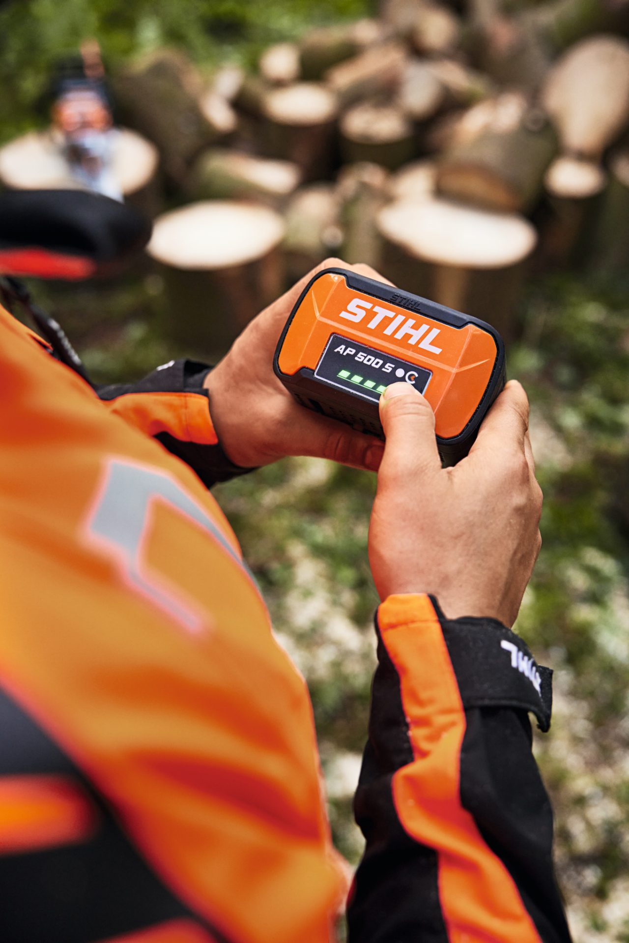 A person holding a STIHL AP 500 S battery in their hands. The LEDs of the charge-level indicator are lit up in green. 