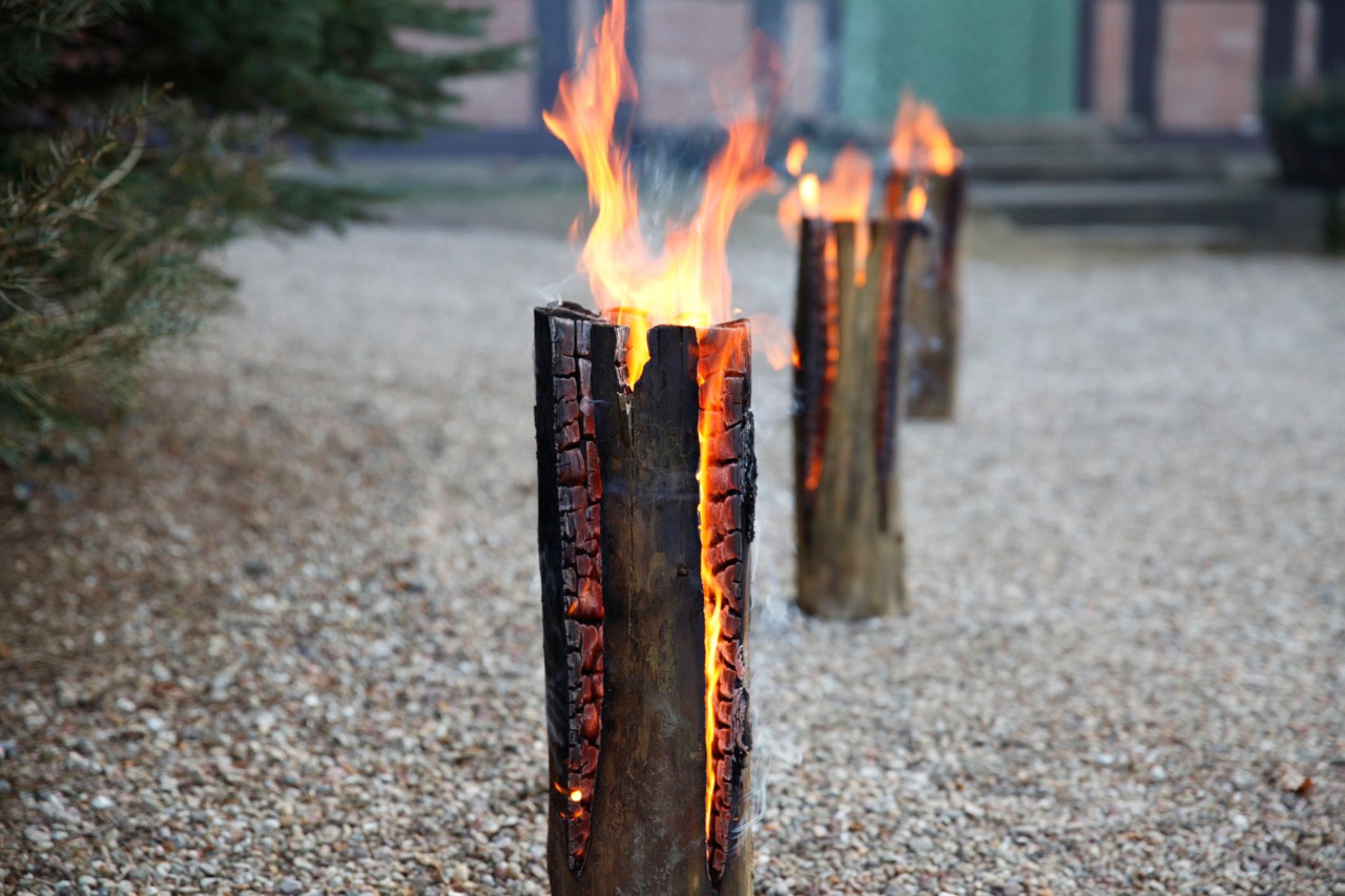 Three burning DIY Swedish fire logs set up on a gravel path