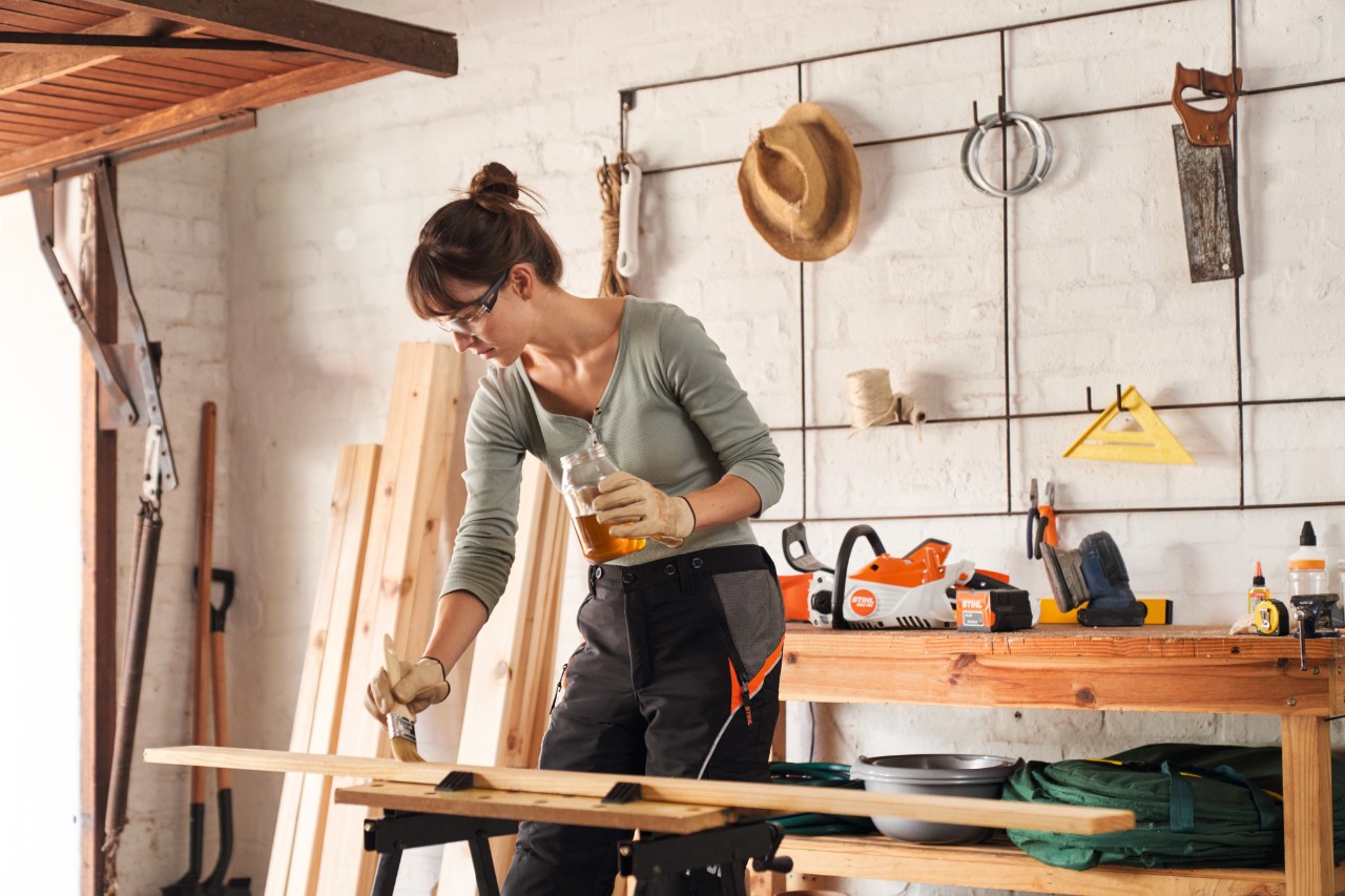 Woman oiling a wooden slat in a workshop