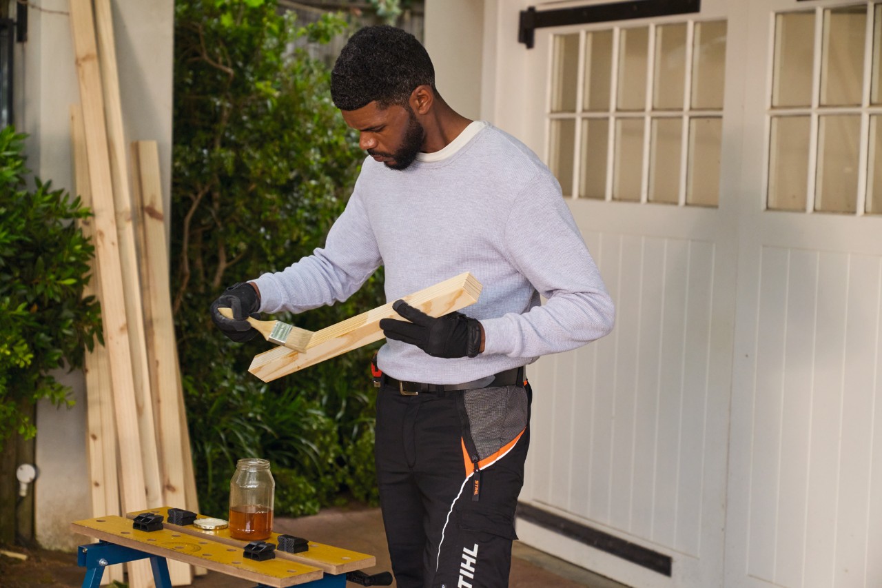 A man brushing a piece of wood with oil