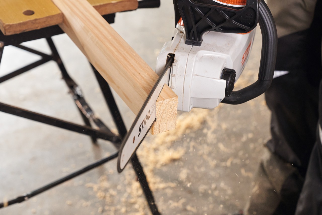 Wood being cut for the feet of a DIY privacy fence with a STIHL MSA 140 cordless chainsaw