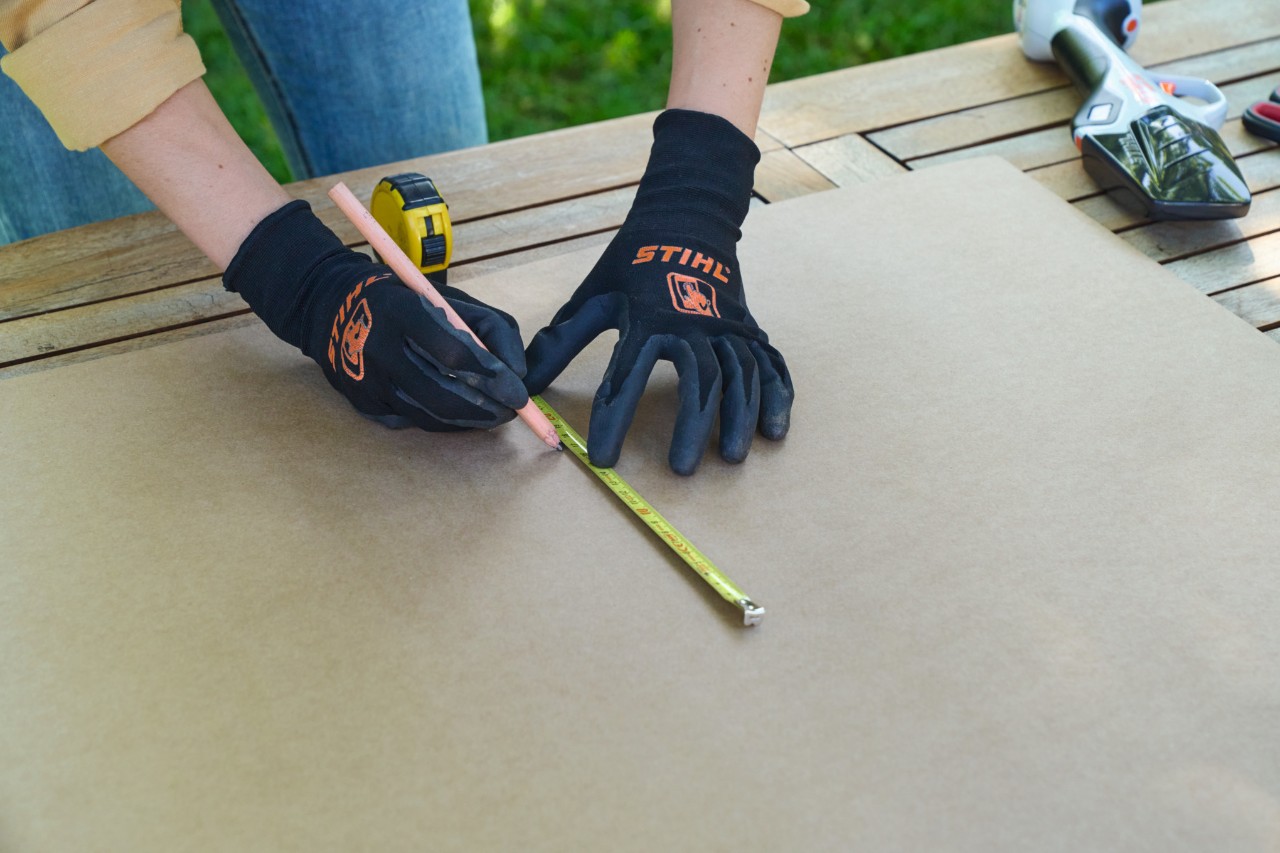 A woman using a tape measure to mark a length on a box with a pen