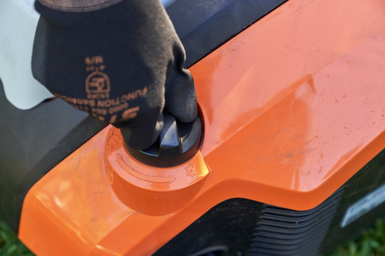 Close-up: a hand wearing STIHL FUNCTION SENSOTOUCH gloves turns the handle of the STIHL RLA 240 cordless lawn scarifier.