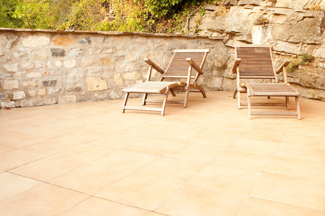 Two wooden recliners on a terrace with natural stone paving