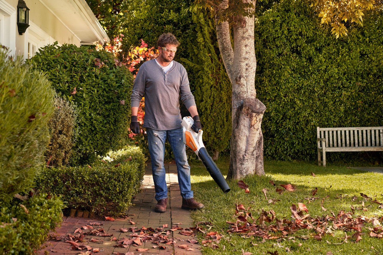Man removing leaves from paving in front of the house with a STIHL BGA 57 cordless blower