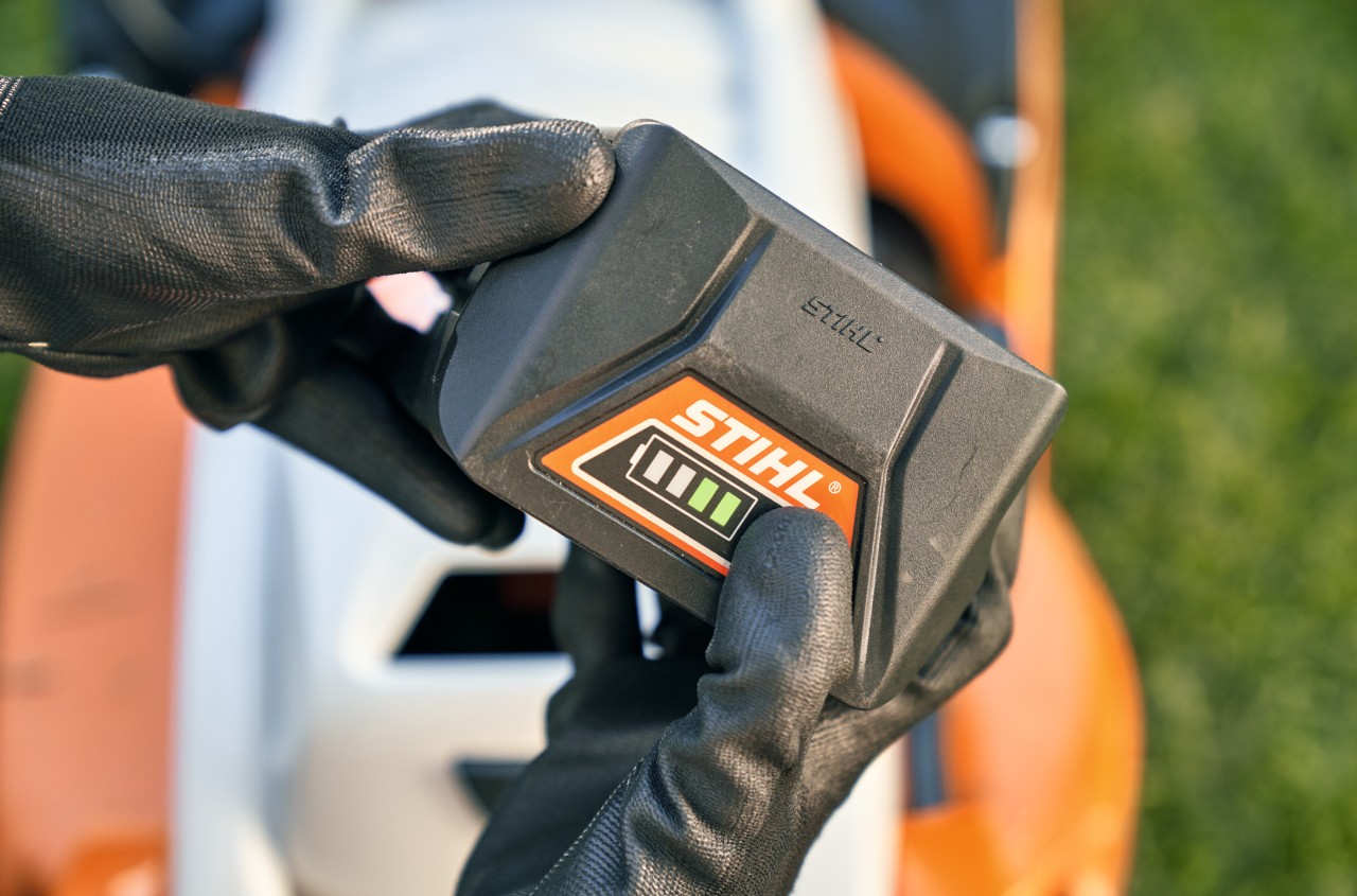 STIHL lithium-ion battery, with a STIHL RMA 339 C cordless lawn mower in the background