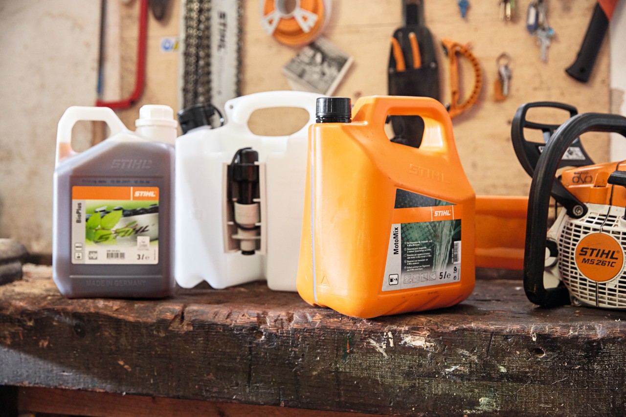 A combination canister on a tool bench in between canisters of STIHL MotoMix and BioPlus chain oil