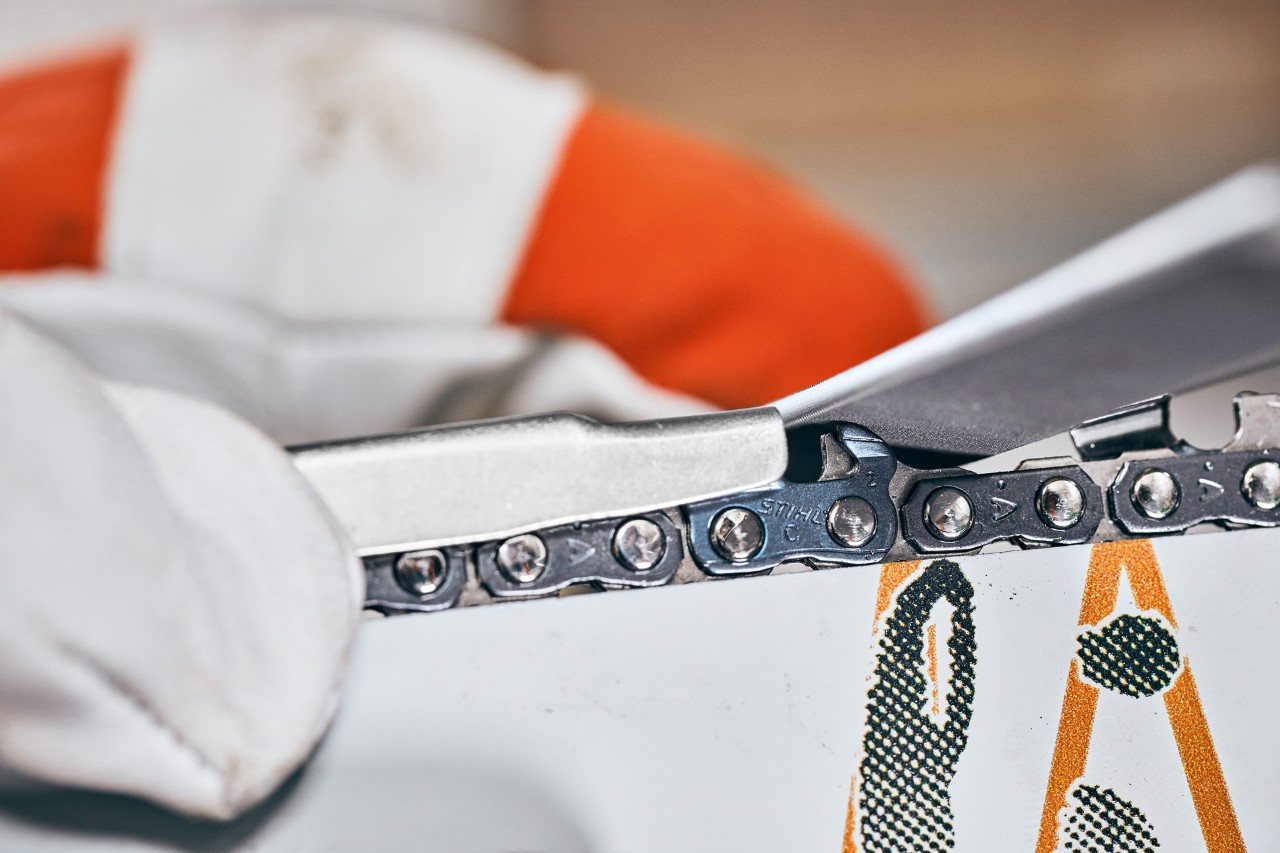Using a filing gauge to sharpen the chainsaw chain with a flat file