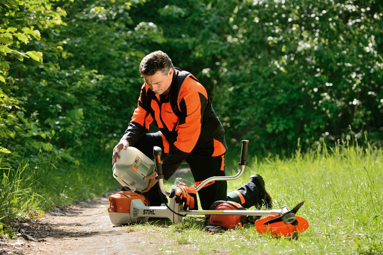 A man refuelling a STIHL brushcutter with a mixture of petrol and oil