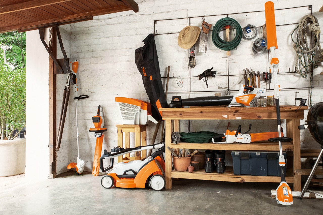 STIHL FSA 56 cordless brushcutter hung up for storage alongside the HSA 56 and HLA 56 cordless hedge trimmers and RMA 339 cordless lawn mower