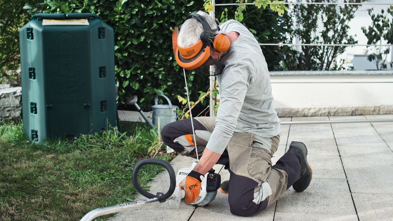 Person wearing protective clothing pulling the starter cord of the STIHL FS 38 petrol brushcutter again