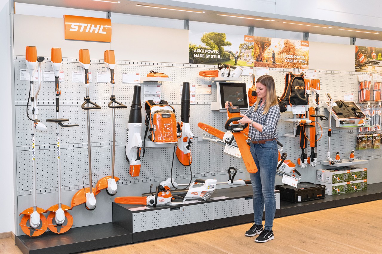 A young woman in front of sales shelving at a STIHL dealer would like a free trial with a STIHL chainsaw 